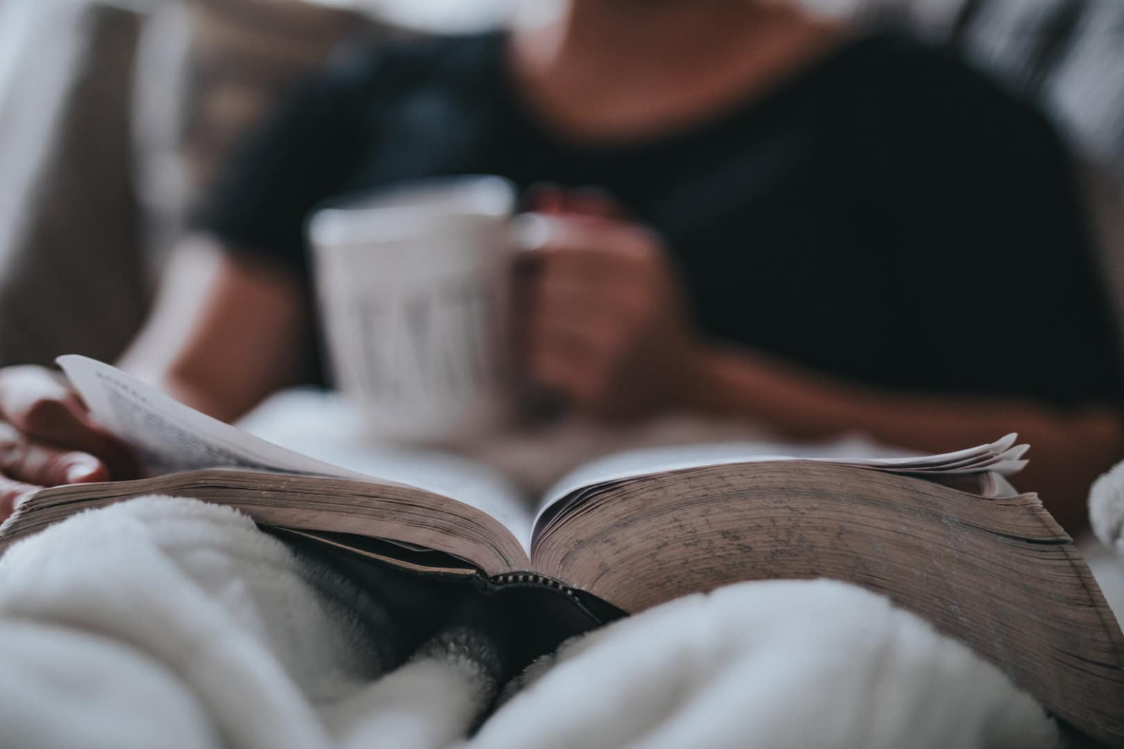 Woman sitting on a couch with coffee and a book relaxing, CBD and OCD
