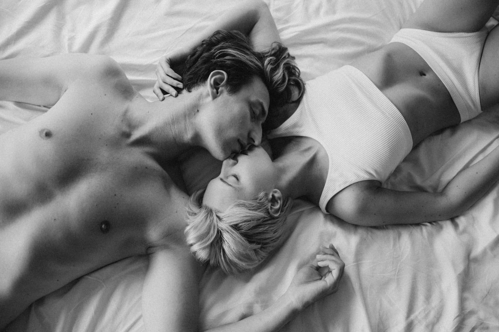 Couple laying down in bed kissing