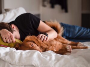 Sleepy man cuddling his dog in bed